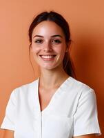 Headshot of a young friendly looking woman wearing a white shirt and smiling confidently against a colored background possibly an office or healthcare setting photo