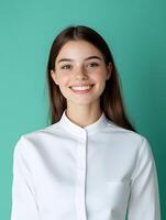 Portrait of a young cheerful and friendly female concierge in a white shirt posing with a welcoming expression on a vibrant green background photo