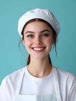Portrait of a young smiling housekeeper or restaurant worker posing confidently against a vibrant teal colored background photo