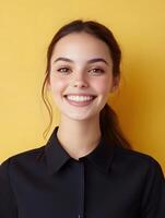 Portrait of a cheerful friendly young woman wearing a professional outfit smiling confidently as a hotel receptionist against a vibrant yellow background photo