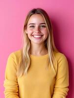 Portrait of a smiling friendly and enthusiastic young woman with blonde hair wearing a yellow sweater and posing against a vibrant pink background photo