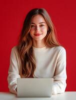 Portrait of a young confident woman with a warm smile working intently on a laptop in a bright modern office environment photo
