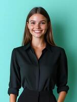 Portrait of a young smiling woman in a black business outfit posing against a bright blue and green background photo
