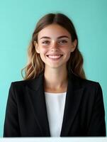 Portrait of a young professional looking woman with a warm welcoming smile dressed in business attire and standing in front of a plain blue background photo
