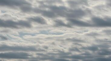 Layers of soft gray and white clouds drift serenely in the expansive sky above. photo