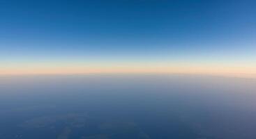 Aerial view of a serene horizon showcasing a gradient of blue sky meeting a foggy earth. photo