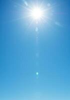 The sun shines brightly in a blue sky creating a fresh, sunny skyscape. photo