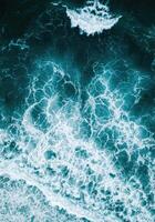 An aerial view showcases the intricate foam patterns of ocean waves in vivid detail. photo
