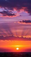 The radiant sun sets, casting long rays through the clouds, creating a stunning display of color. photo