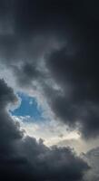 Dark, swirling clouds create a dramatic sky with a glimpse of blue visible, depicting an impressive scene. photo