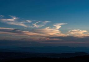 A breathtaking view of a mountain landscape at sunset, with colorful clouds in the sky. photo