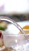 Making hot tea on the kitchen table. Boiling water is poured from the kettle into a cup with a tea bag. Transparent cup of freshly brewed tea on the kitchen table on a sunny day. video