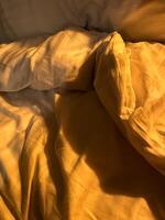Soft golden light illuminates cozy bedding in a tranquil bedroom setting photo