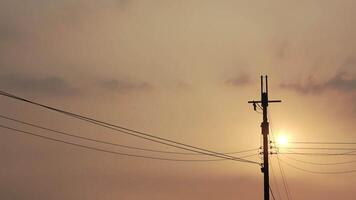As the sun sets, a power pole with extending wires. video