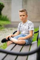 A Thoughtful Boy Sitting on a Bench, Gazing Calmly into the Camera photo