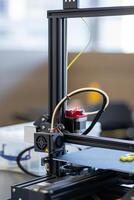View of a working 3D printer mechanism printing a plastic part photo