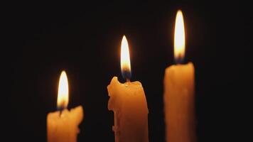 A tranquil scene with three elegantly lit candles casting a soothing and warm glow within the surrounding darkness video
