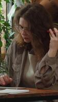 Vertical . Employee listens to voice message with edits from employer using phone, writes notes. Freelancer receives feedback from client. video