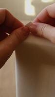 Vertical . Hands bend corner of canvas, stretching unpainted blank canvas on stretcher frame. video