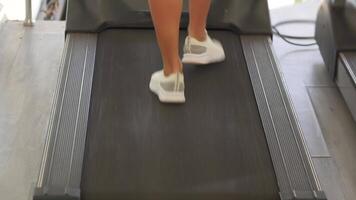 Backside view of treadmill walk in bright gym with focused workout routine video