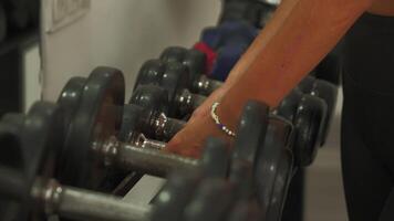 Close-up of hands reaching for dumbbell from rack in gym setting video