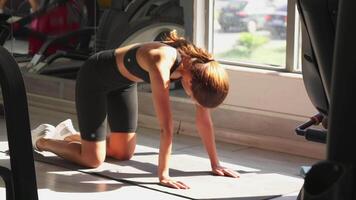Back warm-up exercise on gym floor with sunlight streaming through window video