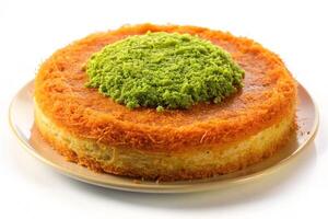 A mouthwatering kunafa with a bright pistachio and mint decoration, served on a silver tray with a smooth white backdrop photo