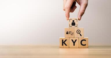Hand arranging wooden blocks with KYC icons, representing Know Your Customer process, digital identity verification, compliance, anti-fraud measures, and customer authentication concepts. photo