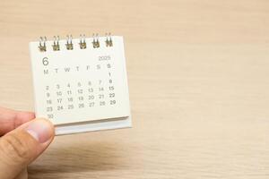 Hand holding mini Calendar for JUNE 2025 background. Calendar concept with 2025 JUN calendar on wooden background. Copy Space for text. photo