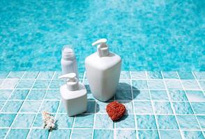 A set of mockups of cosmetics for skin care. A collection of tubes and bottles against a backdrop of bright sunlight and blue tiles by the pool. photo