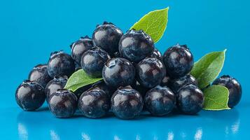 Fresh blueberries arranged in a vibrant blue setting with green leaves for an appealing and nutritious composition photo