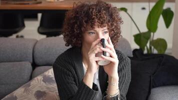 A Contemplative Woman is Enjoying a Warm Beverage While Relaxing at Home in Comfort video