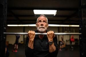 An elderly man is preparing to do pull-ups at the gym, showing strength and determination in his fitness journey. photo