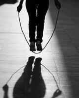 Person skipping rope in silhouette during late afternoon on a city street photo