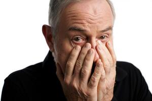 Man showing emotions of distress or worry while covering his face in a neutral setting photo