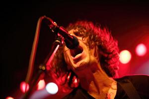 Musician performs passionately on stage with vibrant red lighting during live concert photo