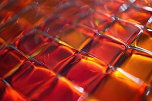 Colorful textured surface featuring glossy red and orange squares reflecting light at close range photo