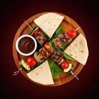 Grilled meat skewer platter with flatbreads and fresh vegetables served on a wooden board photo