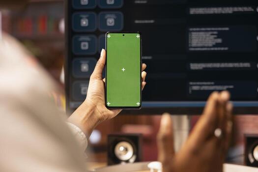 Woman uses isolated screen phone, doing online videocall in front of PC screen with AI LLM chatbot, close up. Person uses large language model program during teleconference on chroma key smartphone photo