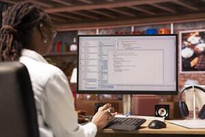 Remotely working engineer in home office looking at UI on computer monitor, typing and executing programming code. Person using coding application to write and test code in modern apartment photo