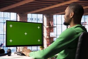 Man using isolated screen PC in home office to write emails. African american person typing on mockup computer keyboard, composing documents in order to deliver finalized project paperwork photo