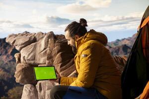 Trekker takes in the panoramic landscape next to isolated mockup screen, where the peaceful mountain scenery and open sky symbolize adventure and perseverance. Wanderlust with tech. photo