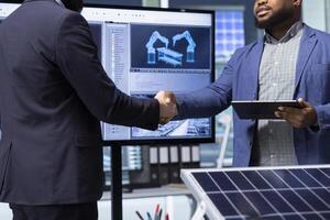 Solar panels plant executive doing handshake with investor, making deal, close up. Photovoltaics factory manager meeting with shareholder to discuss business operations, shaking hands photo