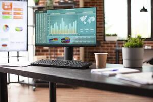 Computer screen displaying marketing strategy research in preparation for a meeting in vacant business office. Brick wall room with nobody is arranged with digital devices showing company analytics. photo
