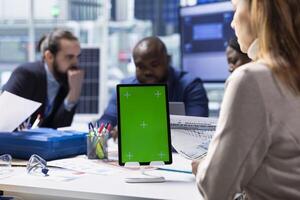 Photovoltaics factory investors analyzing data using isolated screen tablet, reviewing system health metrics. Solar panels plant executives troubleshooting technical issues using mockup device photo