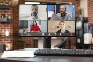 Closeup of virtual group discussion displayed on desktop pc screen in neat office setup. Computer monitor set on vacant desk shows colleagues on a videoconference, attending online training session. photo
