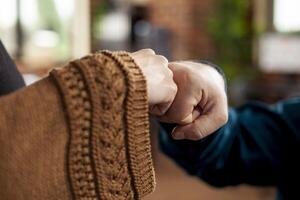 Male and female colleagues engage in fist bump at workspace, maintaining safety and fostering positive connection. Closeup on hands of caucasian people display successful achievement and teamwork. photo
