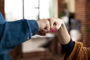 Closeup of hands exchanging fist bump in office, symbolizing unity and cooperation between partners. Two professional individuals making hand gestures, representing successful business collaboration. photo