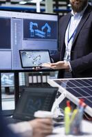 Shareholders planning upgrades using software on devices, optimize factory production layouts. Factory management executives look at assembly facility production lines in CAD program photo
