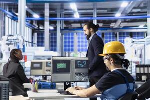 Industrial automation technician in solar panel plant adjusting robotic machinery settings through computer software. Photovoltaics factory employee diagnosing gear performance issues photo